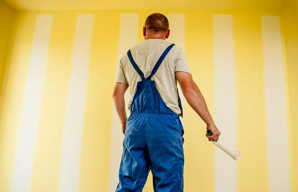 Persona pintando la pared de una habitación con rodillo